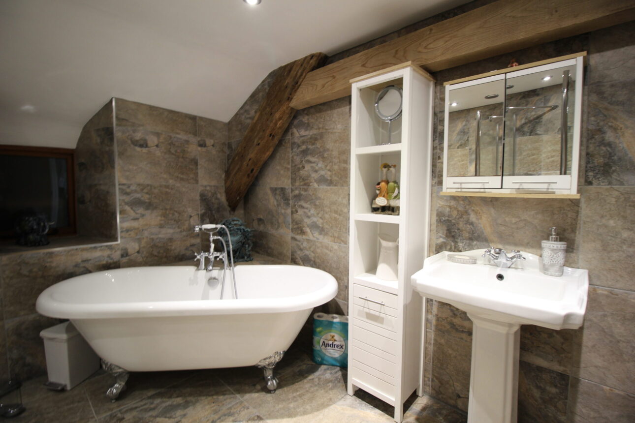 Grey tiled bathroom with with bathtub and oak framed wall supports