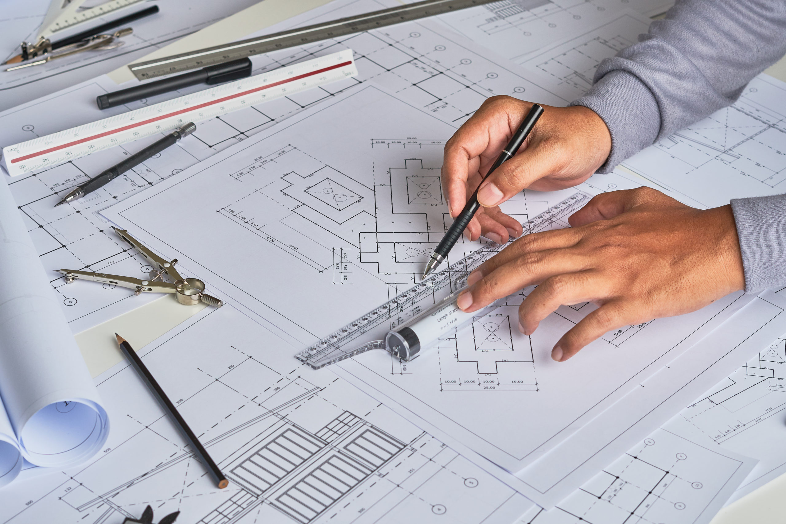 Person measuring Architect plans with ruler on table